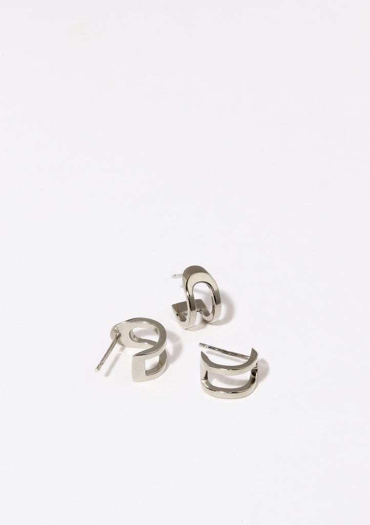 Boucles d'oreilles Maison Mouche au design épuré et architectural, en argent 100% recyclé et tracé, fabriquées dans des ateliers eco-responsables en Italie. Cette mini boucle L'AVENTURE enrobe discrètement l'oreille, elle est un jeu d’oppositions et de ruptures entre courbes et segments. Les biais accentuent les perspectives, la lumière avive les angles et découpe les espaces.