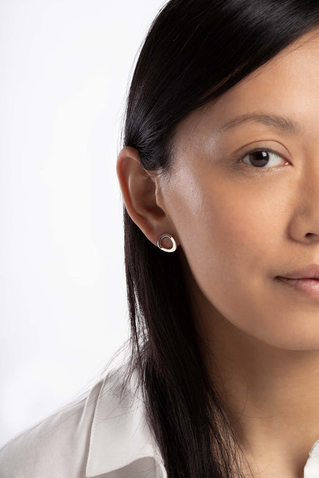 Boucles d'oreille Maison Mouche, cercle ou coeur ? Ces boucles soulignent le dessin de l'oreille et offrent une lecture surprenante de leur forme. Design épuré et minimaliste, en argent 100% recyclé et tracé, fabriquées dans des ateliers eco-responsables en Italie. La collection LE SECRET s’inspire des fascinants procédés optiques de l’anamorphose. Selon l'angle de vue, vous y verrez tantôt un cercle parfait, tantôt un croissant, tantôt un coeur dissimulé.